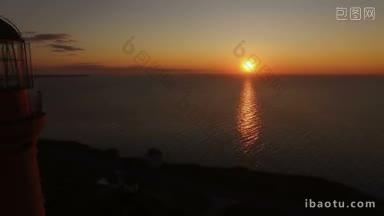 灯塔上的夕阳背景下，在夏天的海上空中飞行的无人机经过灯塔在日落